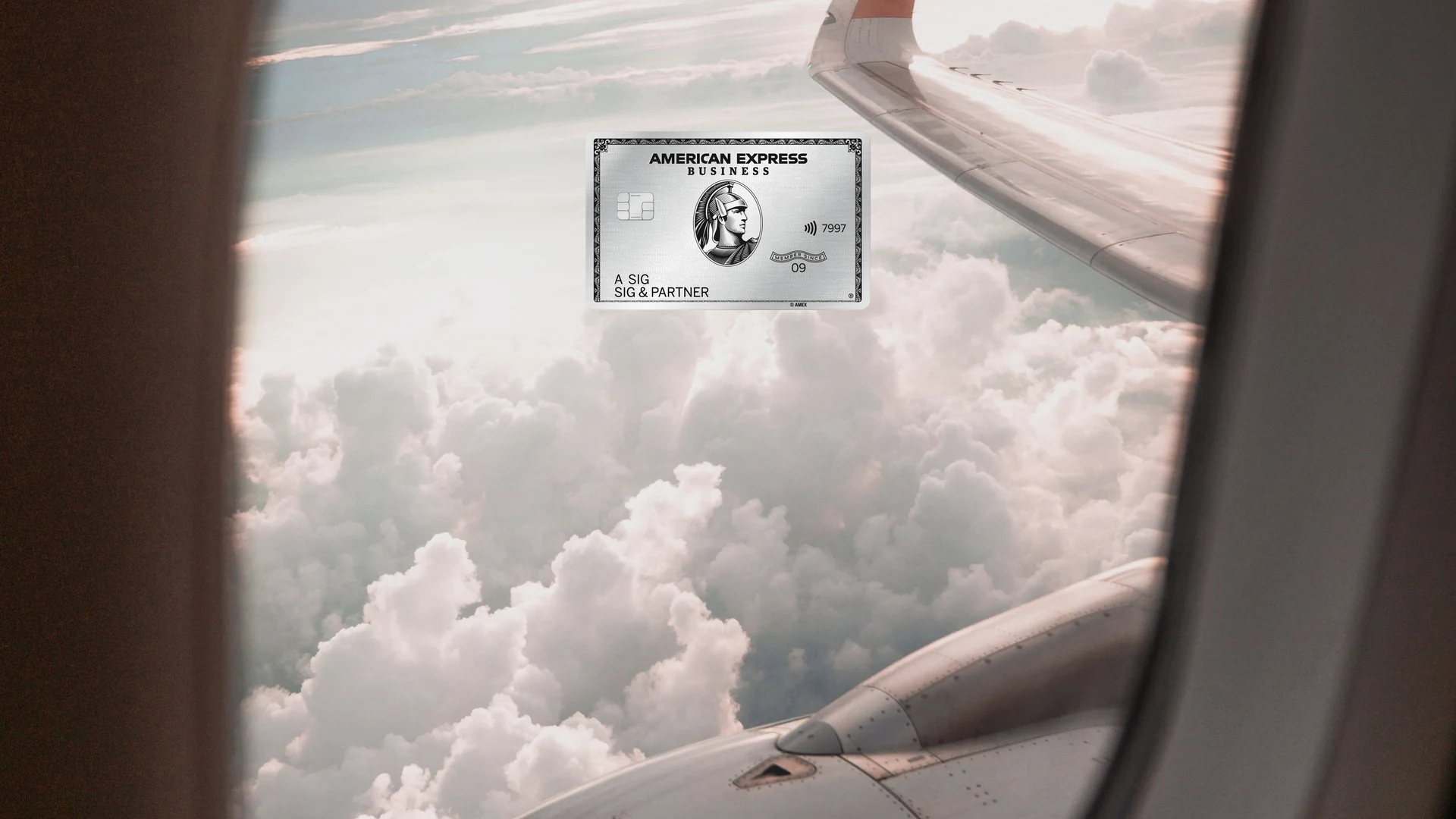 American Express Business Platinum Card vor einer Wolkenlandschaft, aus dem Flugzeugfenster fotografiert