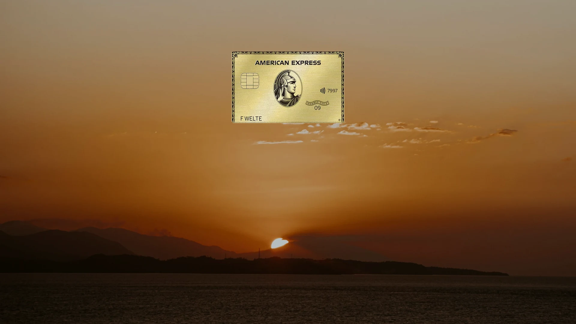 American Express Gold Card vor einem Sonnenuntergang über dem Meer
