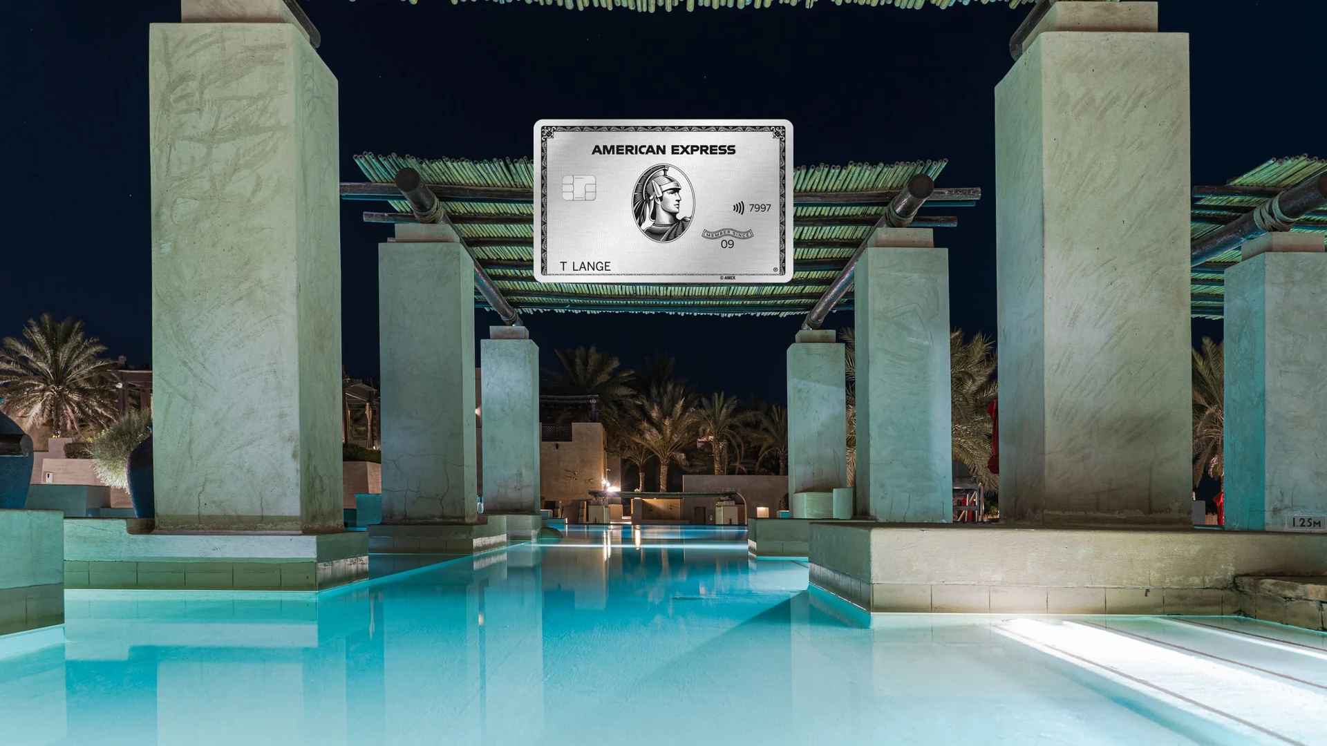 American Express Platinum Card vor einem beleuchteten Hotelpool bei Nacht, Sinnbild für die Guthaben der Karte