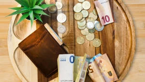 Euroscheine, Münzen und eine braune Geldbörse auf einem Holzbrett, Beitragsbild zum Auszahlen von PAYBACK Punkten