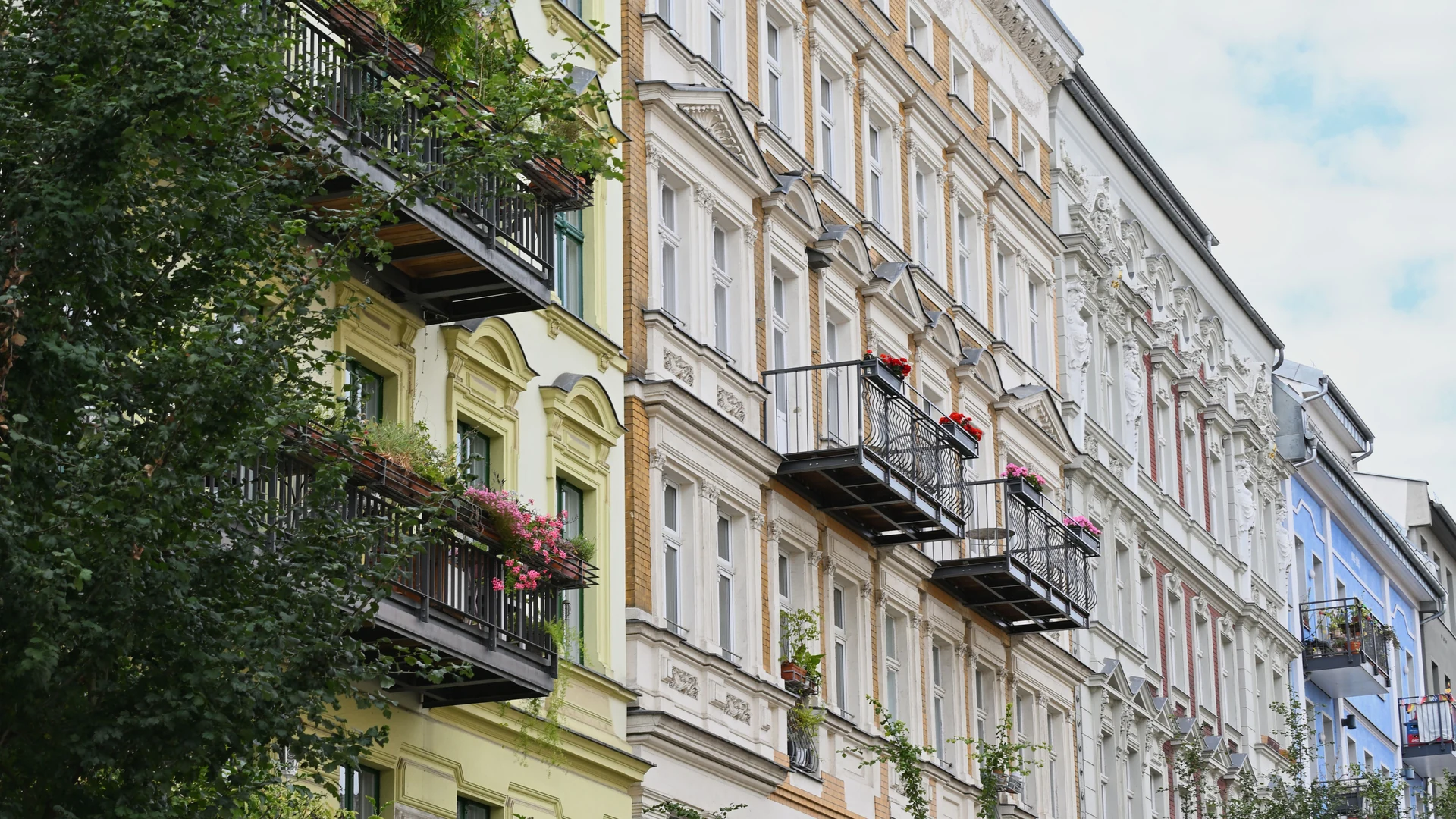 Altbau-Mietshäuser mit Balkonen und Blumenkästen, Beitragsbild zum Thema Miete mit Kreditkarte bezahlen